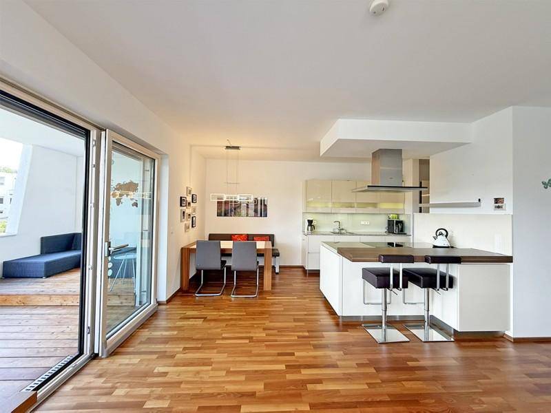 Offener Wohn-Essbereich mit moderner Einbauküche, Holzboden und Zugang zur Terrasse.