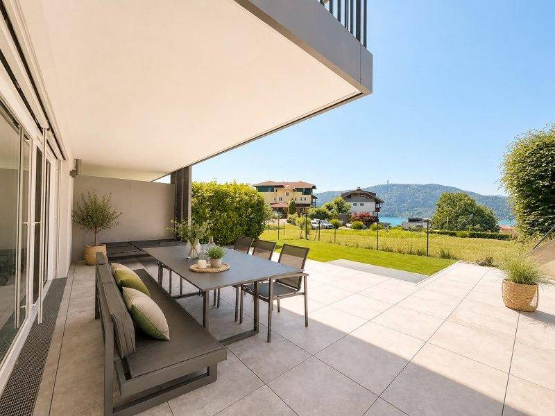 Moderne Terrasse mit großem Esstisch und Sitzbank, bietet weiten Blick auf den See und die Berge.