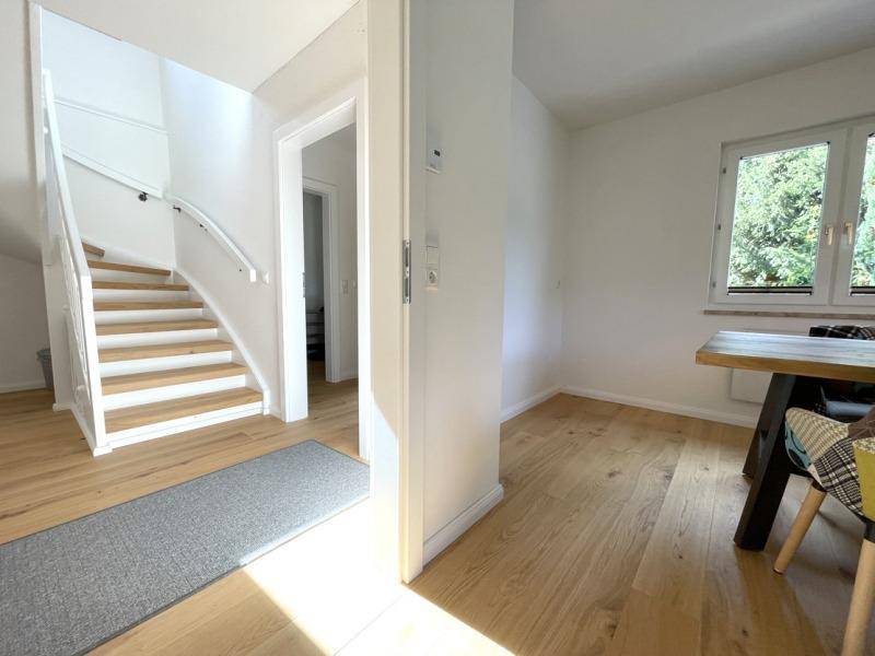 Heller Eingangsbereich mit Holztreppe und Holzboden, der zu den oberen Etagen führt.