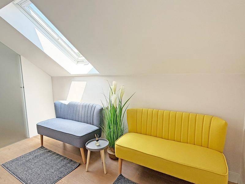 Gemütlicher Sitzbereich im Dachgeschoss mit Dachfenster, schräger Decke und farbigen Sofas.