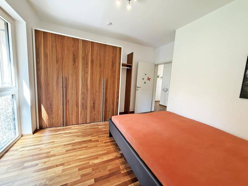 Schlafzimmer mit Holzboden, Einbauschränken und Zugang zu einem weiteren Raum.