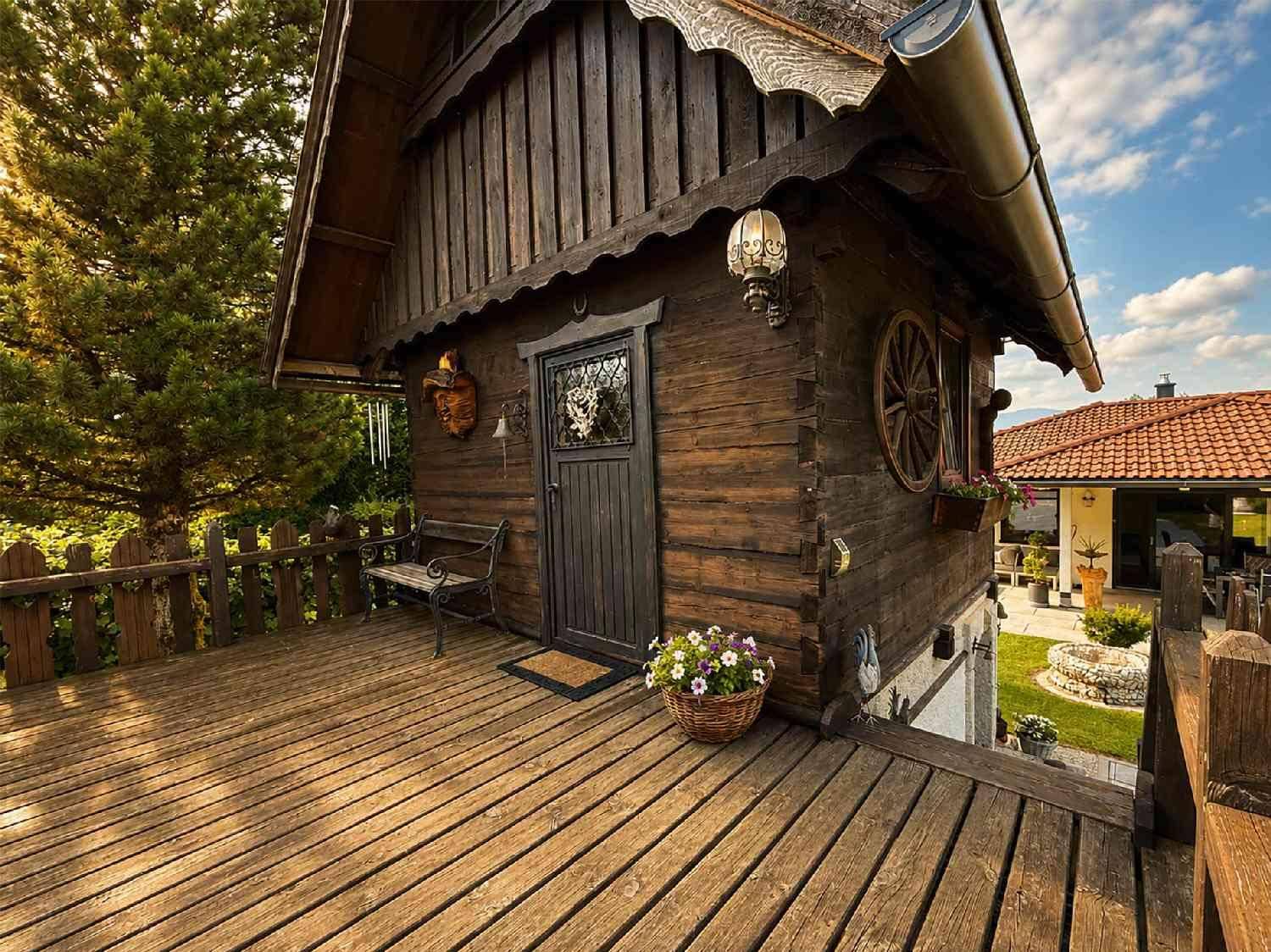 Rustikales Holzhaus mit einer charmanten Holzterrasse und Blumenkorb.