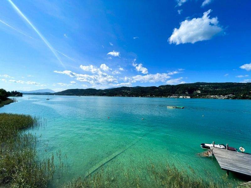 Idyllischer Panoramablick auf den türkisblauen See und die umliegende Berglandschaft unter strahlendem Himmel.