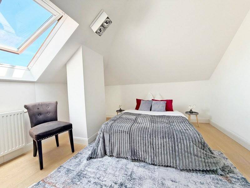 Gemütliches Schlafzimmer im Dachgeschoss mit schräger Decke, Dachfenster und hellem Holzboden.
