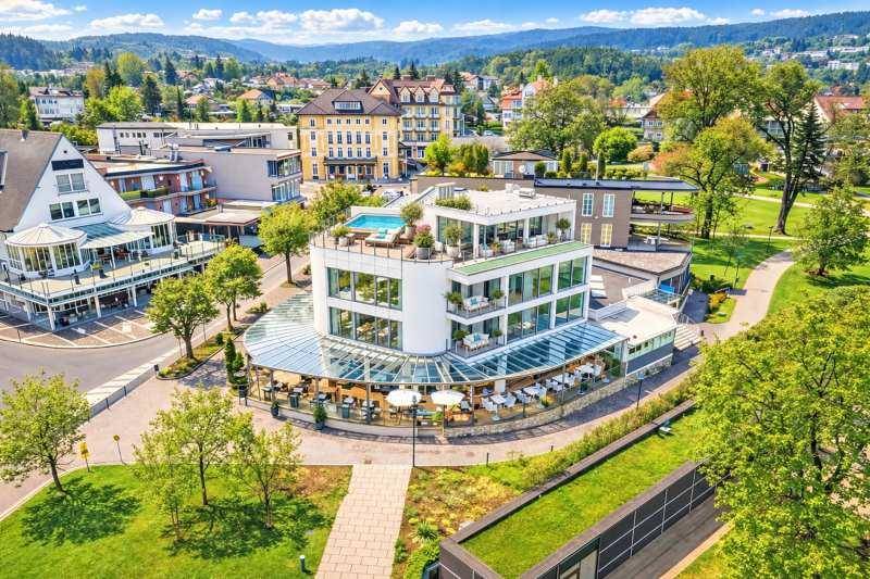 Moderne Architektur mit Dachterrasse und Pool, umgeben von Grünflächen und städtischer Bebauung.