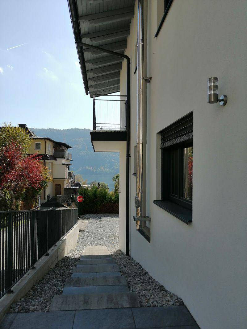 Seitenansicht des Gebäudes mit Außentreppe, Balkon und modernen Fenstern mit Rollläden.