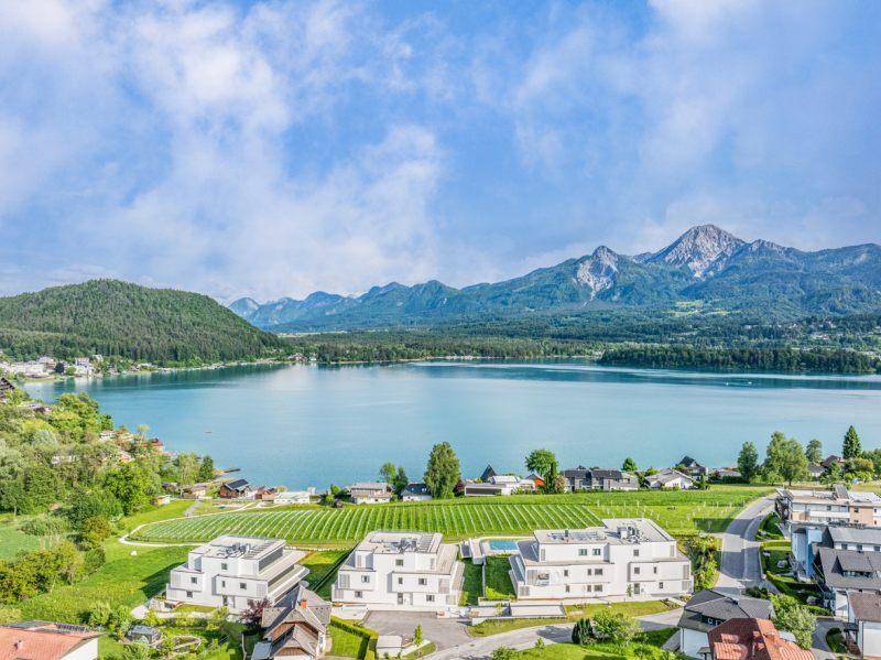 Weitläufiger Panoramablick auf den See, umgeben von Bergen und modernen Wohngebäuden.