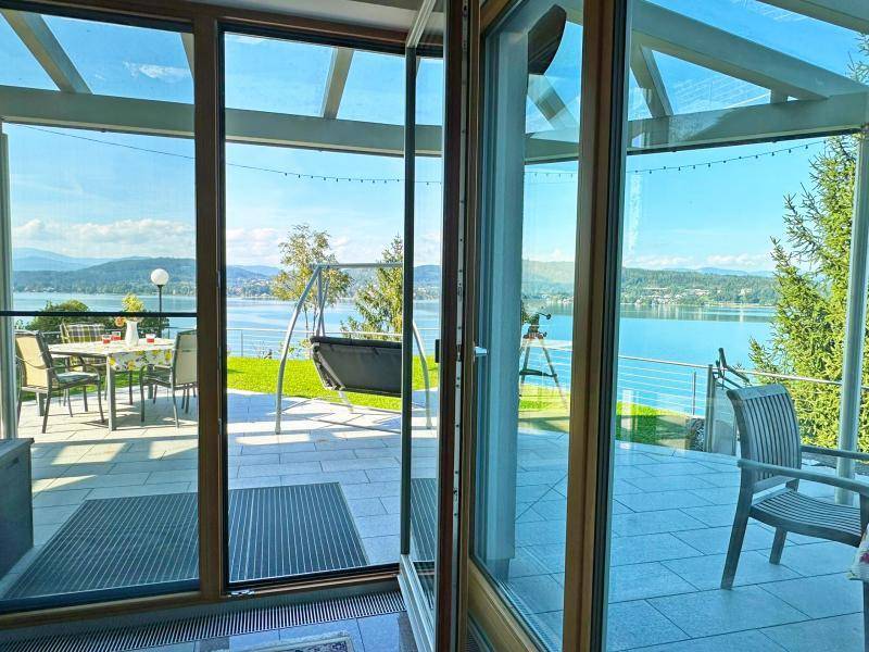 Heller Innenraum mit großen Glasfronten, die den Blick auf die Terrasse und den See freigeben.