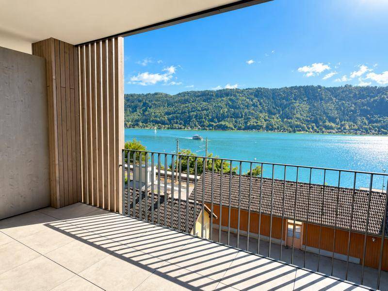 Geräumiger Balkon mit Fliesenboden und atemberaubendem Blick auf den See und die umliegenden Berge.