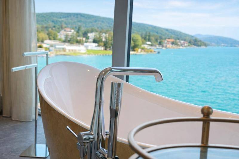 Elegantes Badezimmer mit freistehender Badewanne und einem beeindruckenden Blick auf den See.