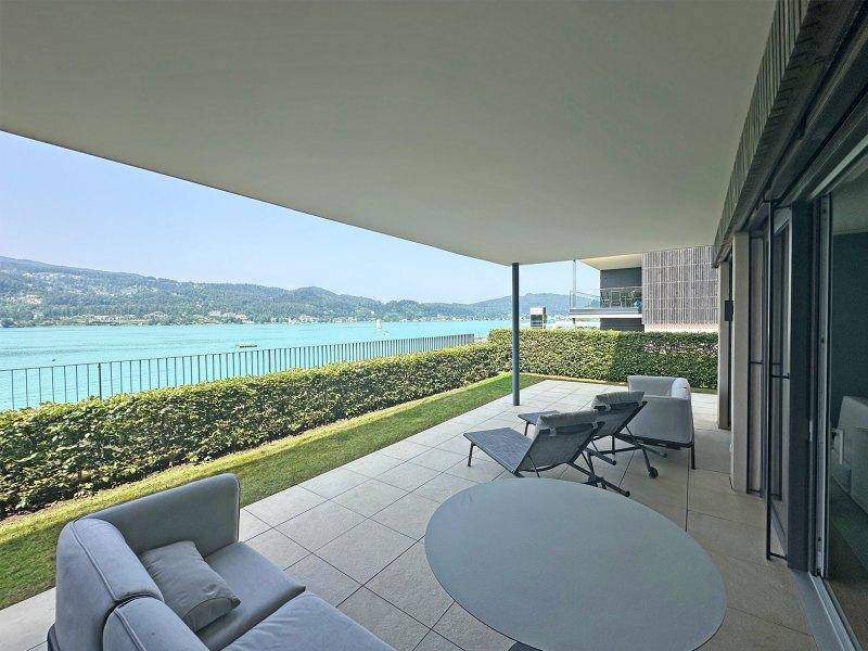 Geräumige überdachte Terrasse mit modernen Loungemöbeln und weitem Blick auf den See.