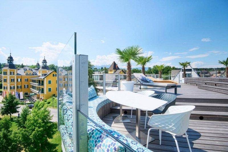 Stilvolle Dachterrasse mit bequemen Sitzgelegenheiten, Palmen und Panoramablick auf die Umgebung.