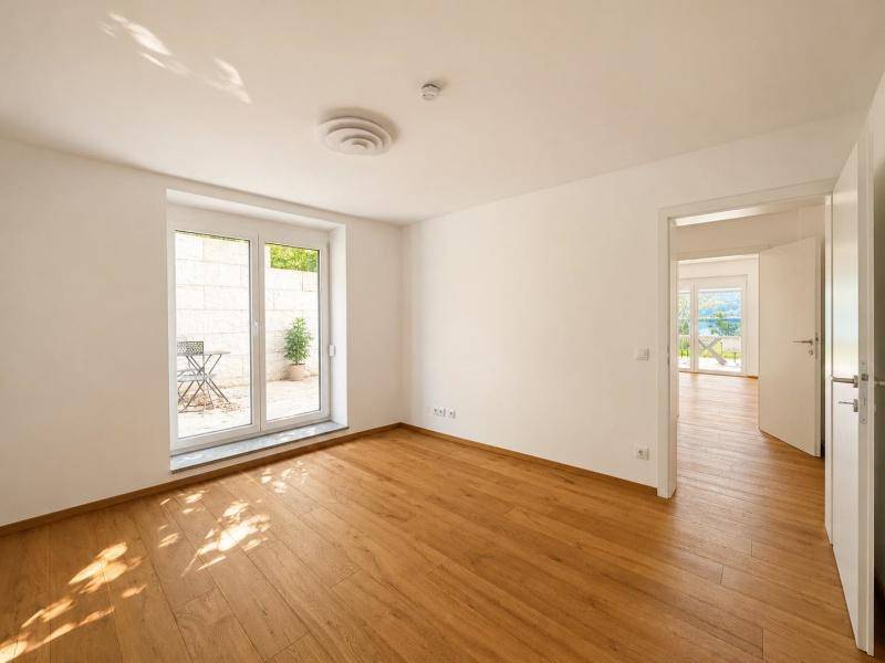 Heller Raum mit Holzboden und Zugang zu einer kleinen Terrasse, ideal als Wohn- oder Schlafzimmer.