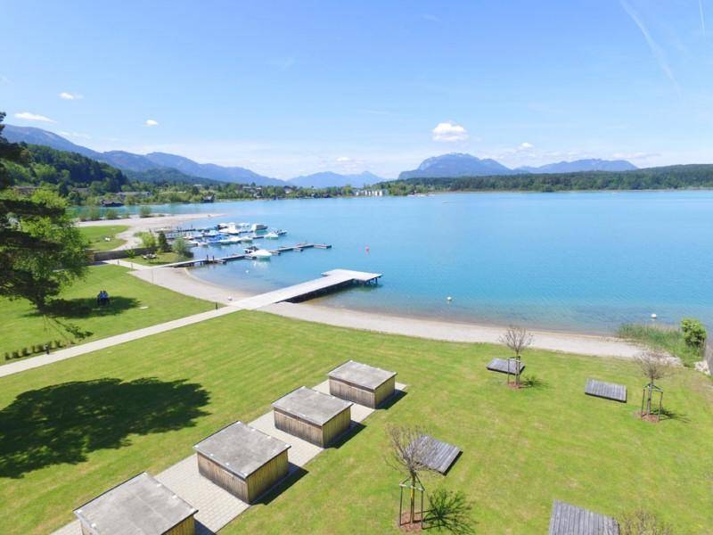 Weitläufige Rasenfläche am Seeufer mit Blick auf den See und die umliegenden Berge.