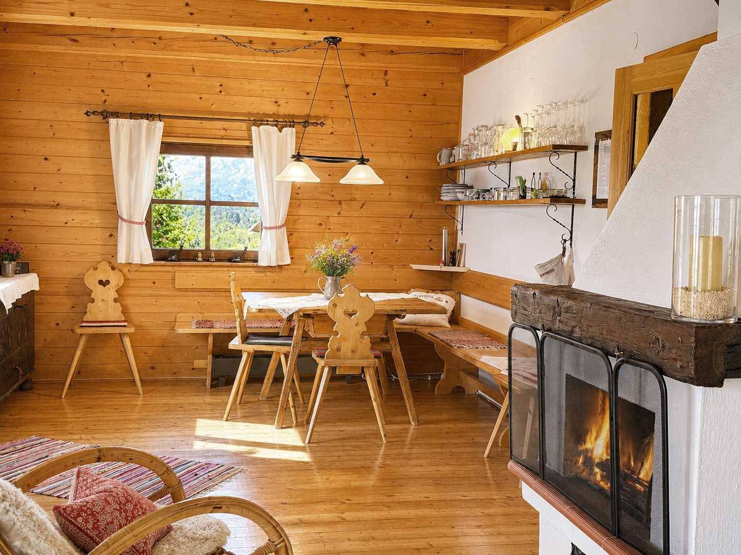 Gemütlicher Wohn- und Essbereich im alpinen Stil mit Holzwänden, Kamin und traditionellen Möbeln.