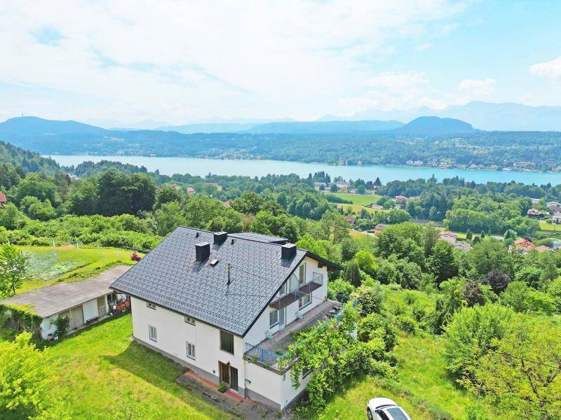 Freistehendes Haus mit Balkonen und weitem Blick auf den See und die umliegende Berglandschaft.