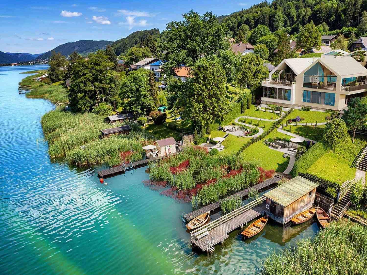 Luftaufnahme der modernen Seevilla mit weitläufigem Garten, privaten Bootsstegen und direktem Seezugang.