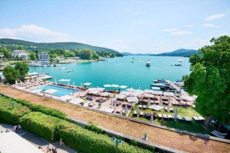 Weitläufiger Poolbereich mit Liegestühlen und Sonnenschirmen direkt am Ufer des Sees.