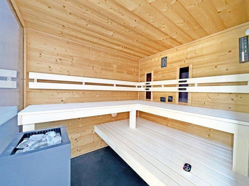 Geräumige Holzsauna mit mehrstufigen Bänken und Saunaofen für entspannende Momente.