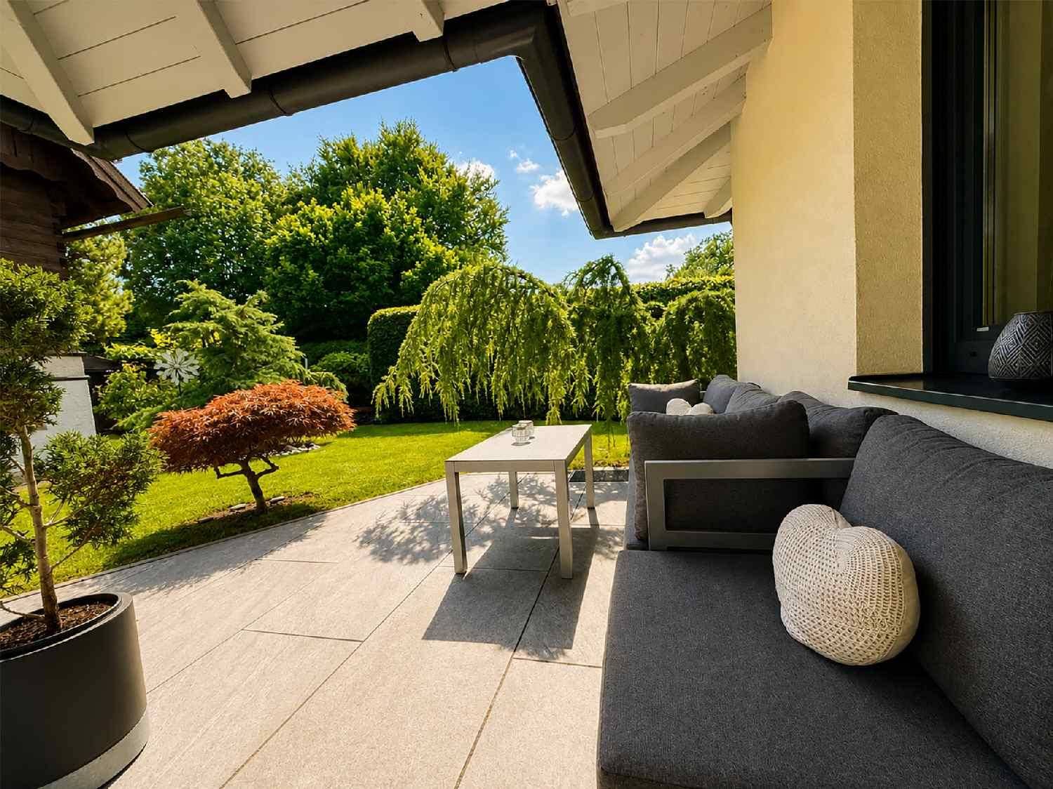Gemütliche überdachte Terrasse mit Lounge-Möbeln und Blick in den Garten.