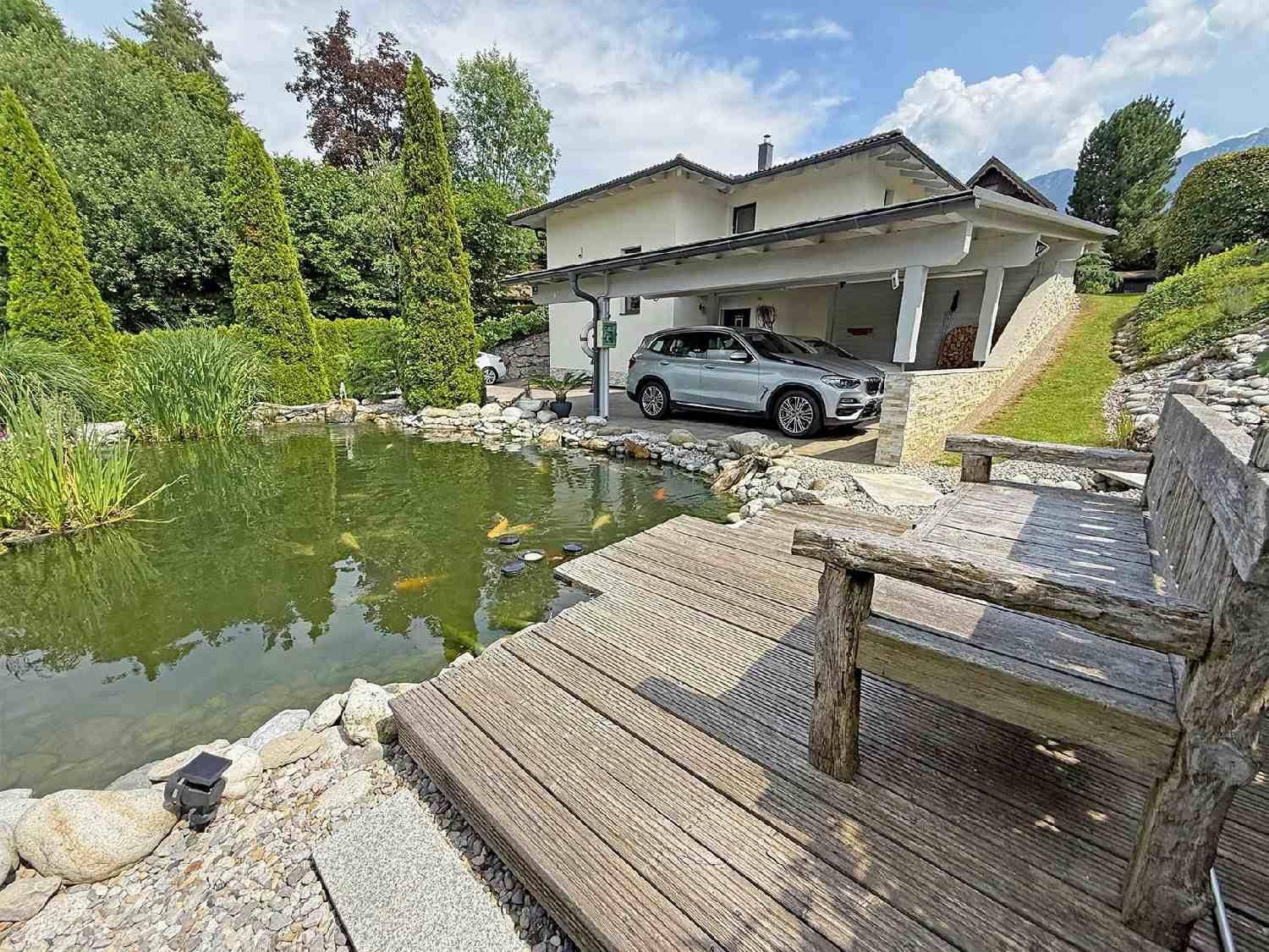 Idyllischer Gartenteich mit Holzsteg und Blick auf das Haupthaus.