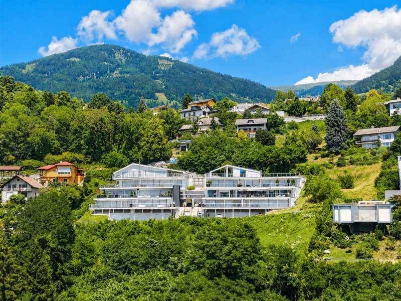 Weitläufige Ansicht der modernen Wohnanlage, eingebettet in die grüne Hügellandschaft mit Bergblick.
