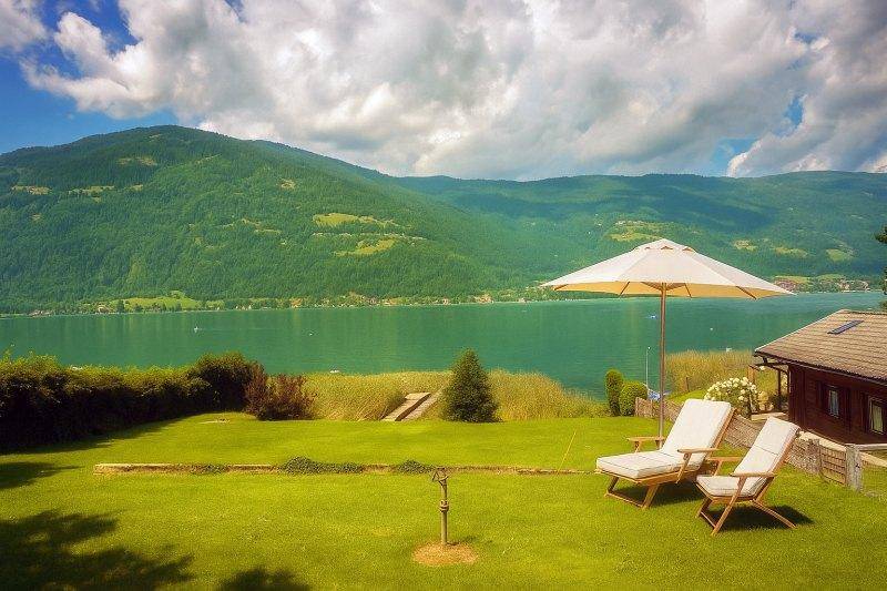 Sonniger Gartenbereich mit Liegestühlen und Sonnenschirm, ideal zum Entspannen mit Seeblick.