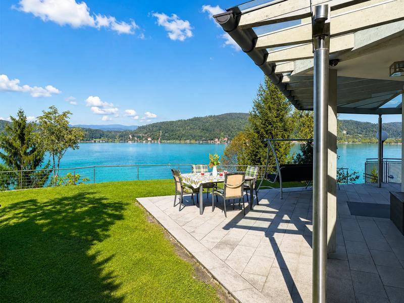 Geräumige Terrasse mit Essbereich und Rasenfläche, ideal für Mahlzeiten mit Seeblick.