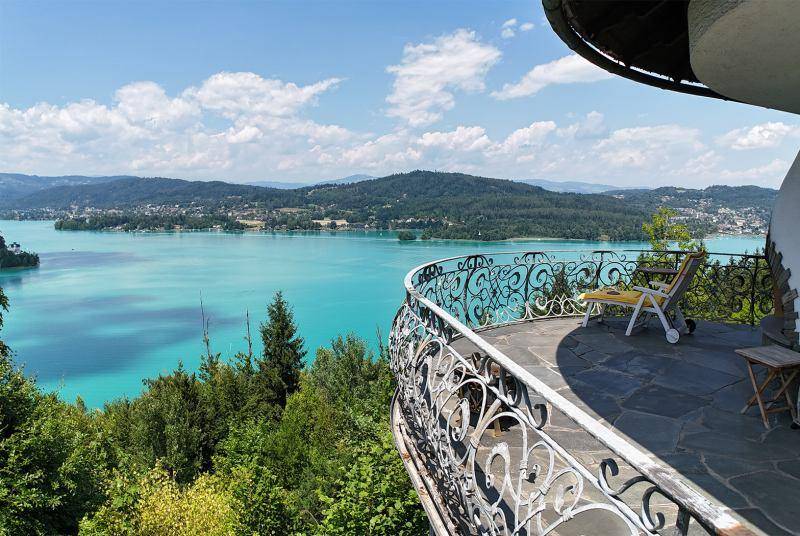 Geräumige Terrasse mit Steinboden und schmiedeeisernem Geländer, die einen weiten Blick auf den See und die umliegenden Berge bietet.