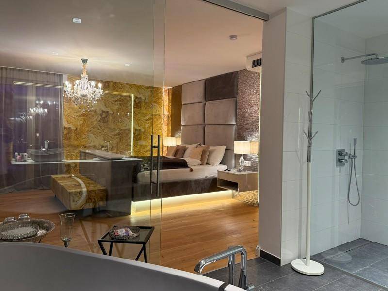 Luxuriöses Schlafzimmer mit offenem Badbereich, freistehender Badewanne und stilvoller Beleuchtung.