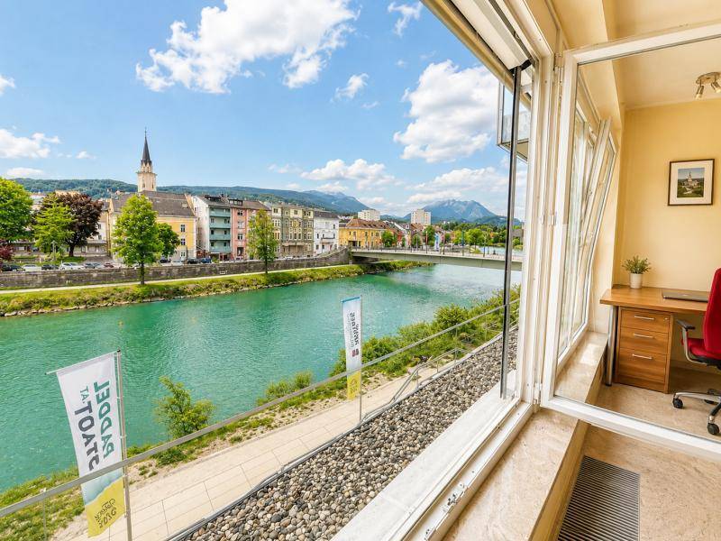 Helles Büro mit Schreibtisch und großem Fenster, das einen weiten Blick auf den Fluss und die Stadt bietet.