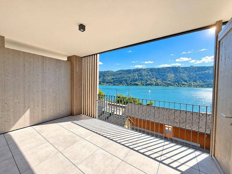 Geräumiger Balkon mit Fliesenboden und Holzelementen bietet einen weiten Blick auf den See.