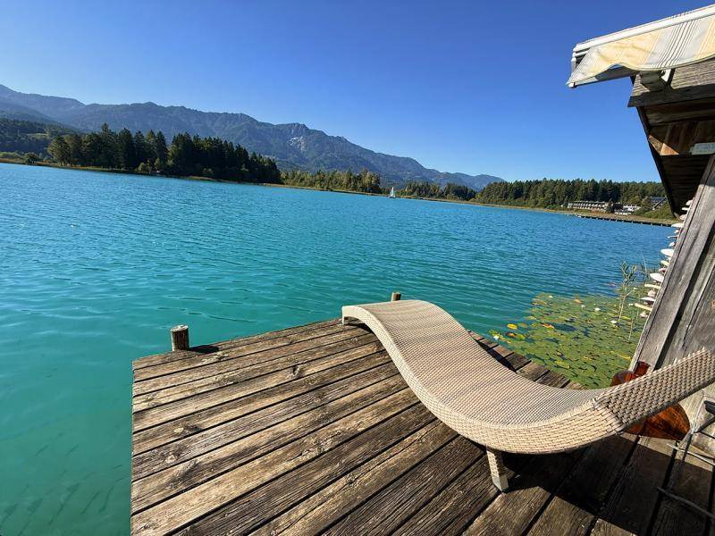 Entspannungsbereich auf dem Holzsteg direkt am türkisfarbenen See mit Bergblick.