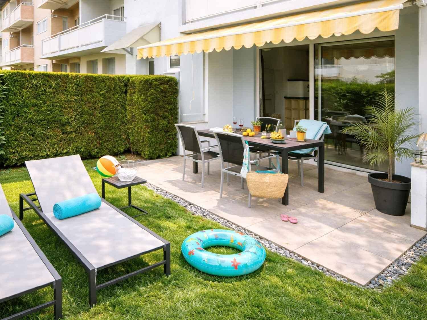 Großzügige Terrasse mit Essbereich und Liegestühlen, umgeben von einem gepflegten Rasen.