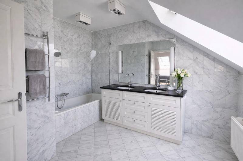 Luxuriöses Badezimmer mit Marmorfliesen, Doppelwaschbecken, Badewanne und Dachfenster.