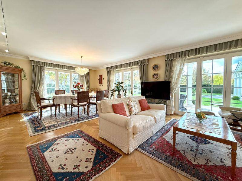 Geräumiger Wohn-Essbereich mit Parkettboden, eleganten Möbeln und großen Fenstern zum Garten.