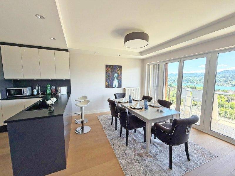 Moderne offene Küche mit Essbereich, dunklen Arbeitsplatten und Zugang zu einem Balkon mit Aussicht.