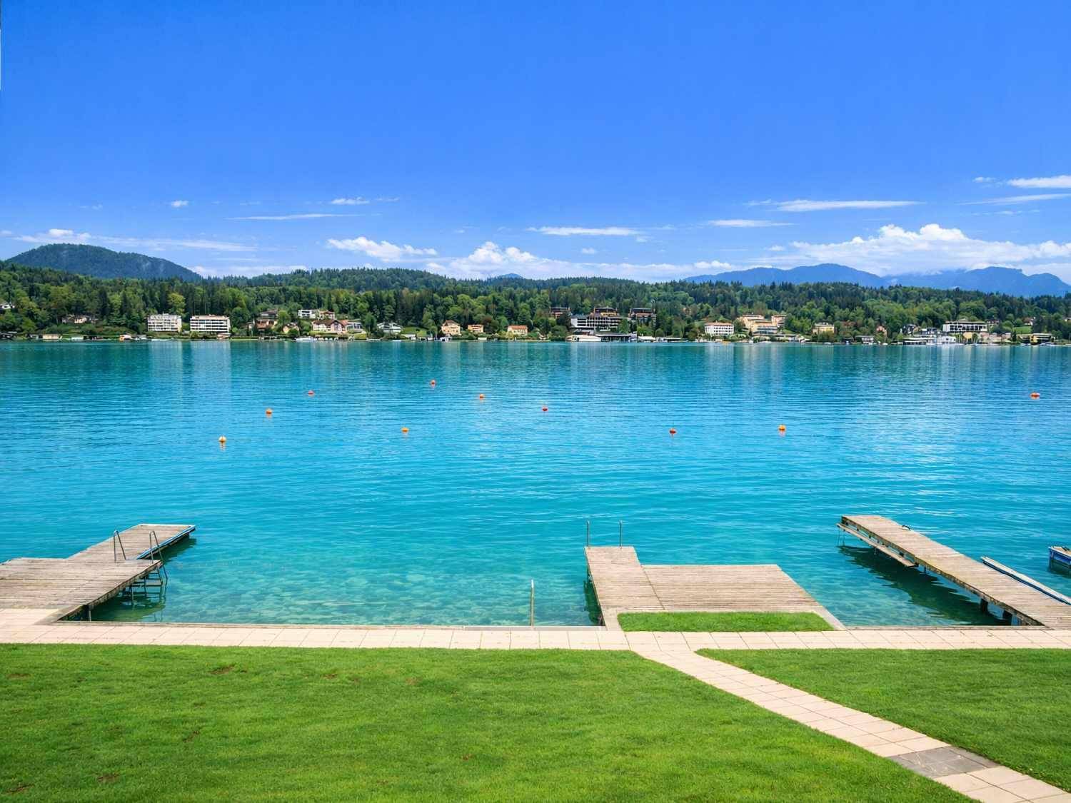 Weitläufiger Seeblick mit mehreren Holzstegen und Zugang zum klaren Wasser.