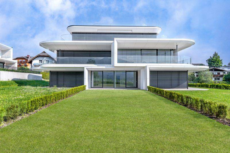 Elegante moderne Villa mit minimalistischer Architektur, großen Fensterfronten und gepflegtem Vorgarten.