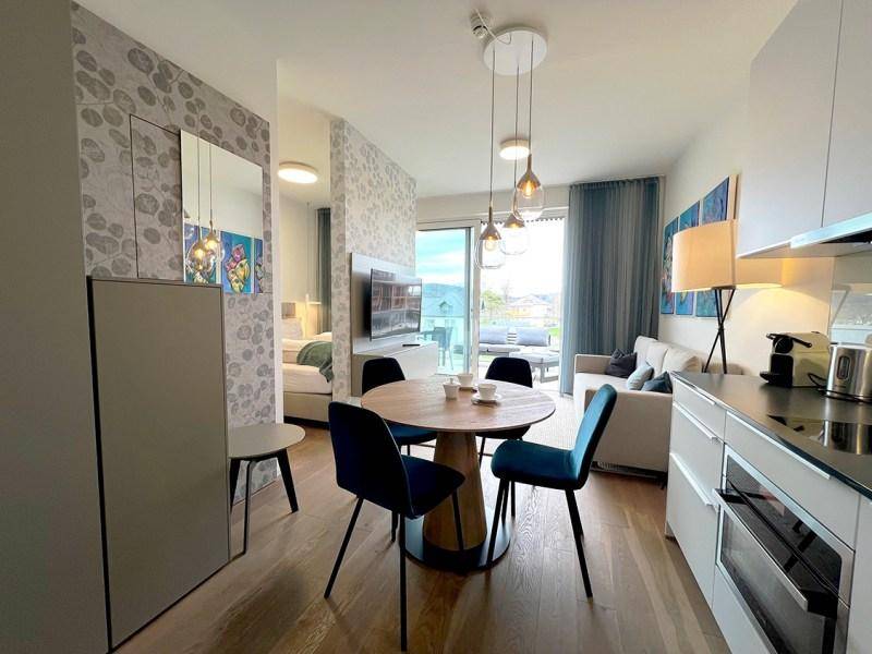 Heller Wohn- und Essbereich mit integrierter Küchenzeile und Zugang zu einem Balkon.
