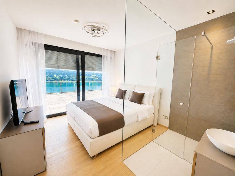 Helles Schlafzimmer mit Seeblick, integriertem Duschbereich und modernen Möbeln, ideal für entspannte Nächte.