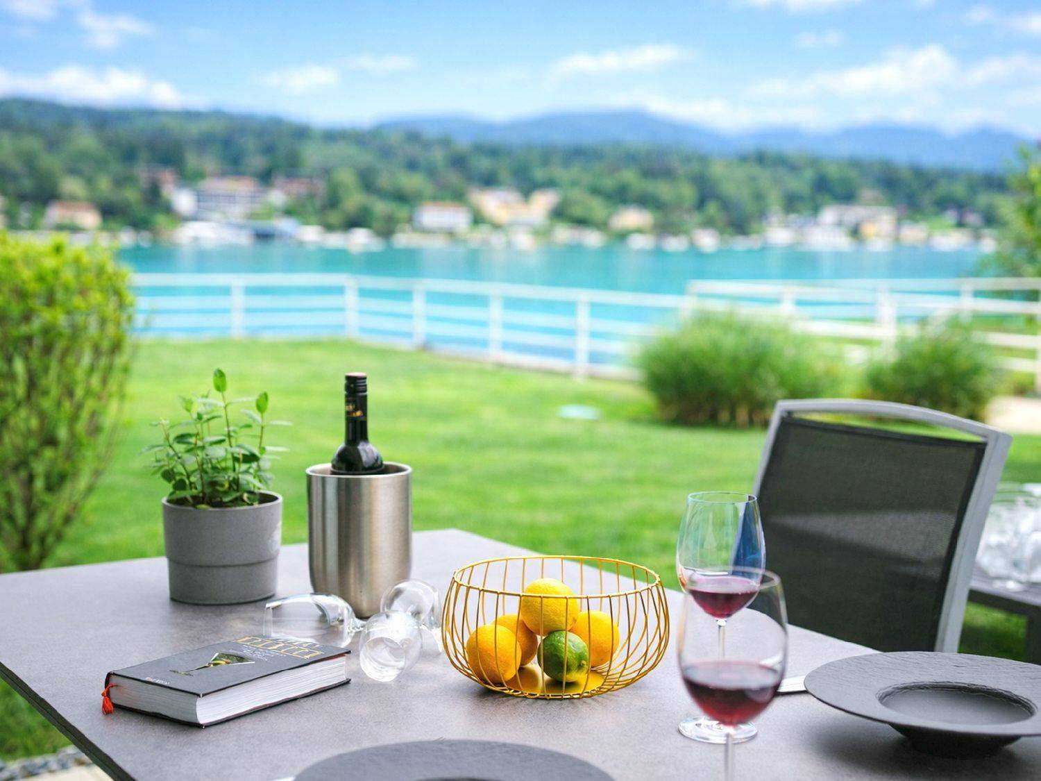Gemütlicher Essbereich im Freien mit Wein und Obst, mit malerischem Seeblick im Hintergrund.