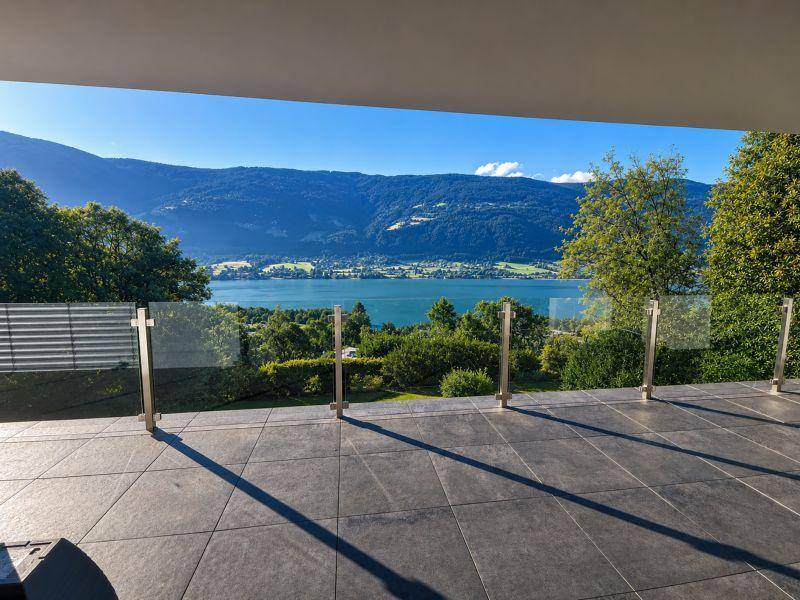 Geräumige Terrasse mit Fliesenboden und Glasgeländer bietet einen weiten Seeblick.