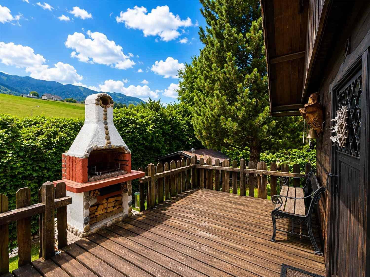 Holzterrasse mit gemauertem Grill und Bergblick, ideal für gesellige Abende.