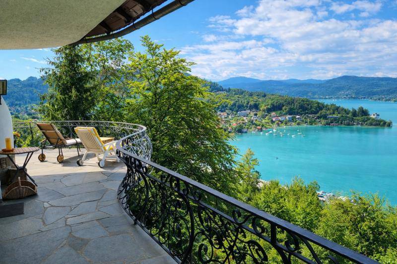 Sonniger Balkon mit schmiedeeisernem Geländer und bequemen Liegestühlen, bietet einen weiten Seeblick.