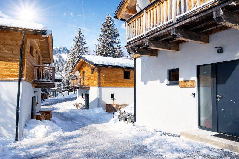 Außenansicht von modernen Chalets mit Holzfassaden und Balkonen in verschneiter Umgebung.