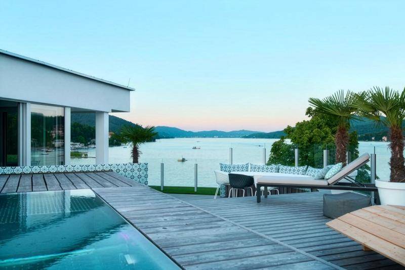Luxuriöser Poolbereich auf der Dachterrasse mit Holzdeck, Liegestühlen und Seeblick.