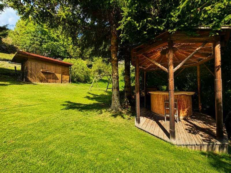 Großer Gartenbereich mit Holzpavillon, Whirlpool und einem Geräteschuppen im Hintergrund.