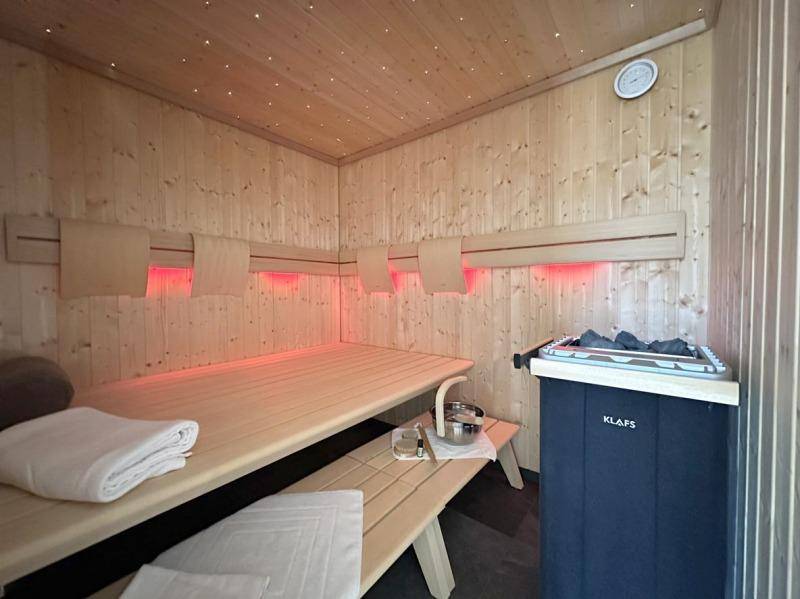 Holzvertäfelte Sauna mit traditionellem Ofen und indirekter Beleuchtung für pure Entspannung.