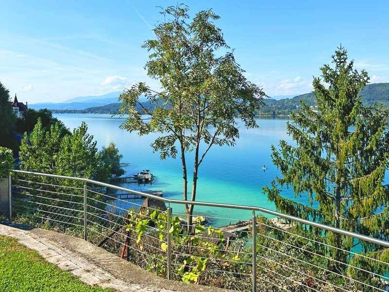Grüner Gartenbereich mit Bäumen und moderner Brüstung, bietet einen schönen Blick auf den See.